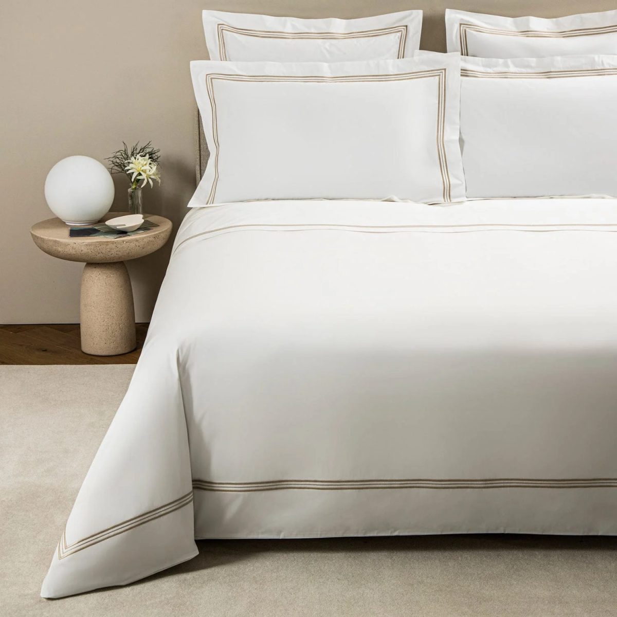 A double bed with luxury white bed linen with gold details