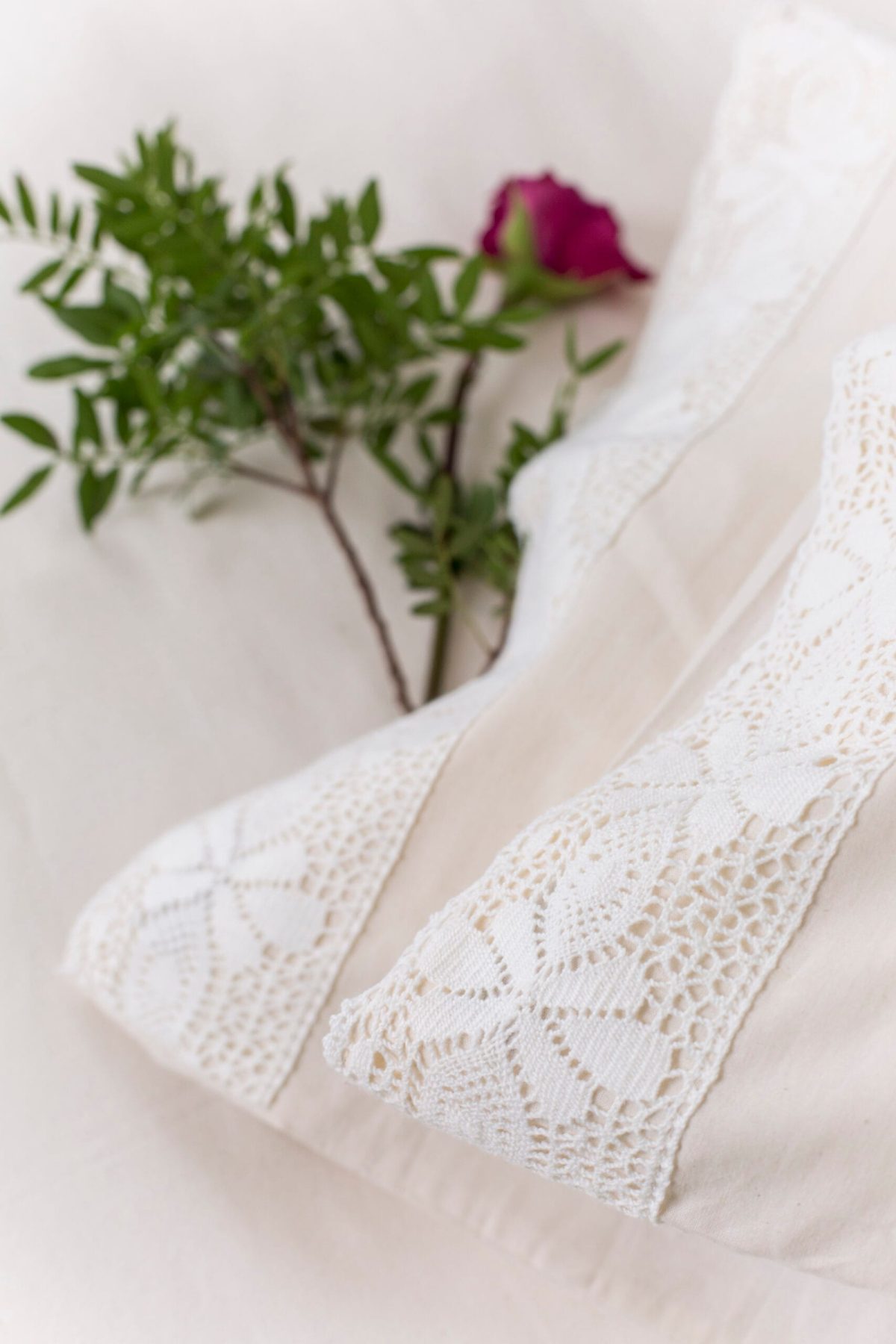 White embroidered bed linen with a white lace detail and a red rose